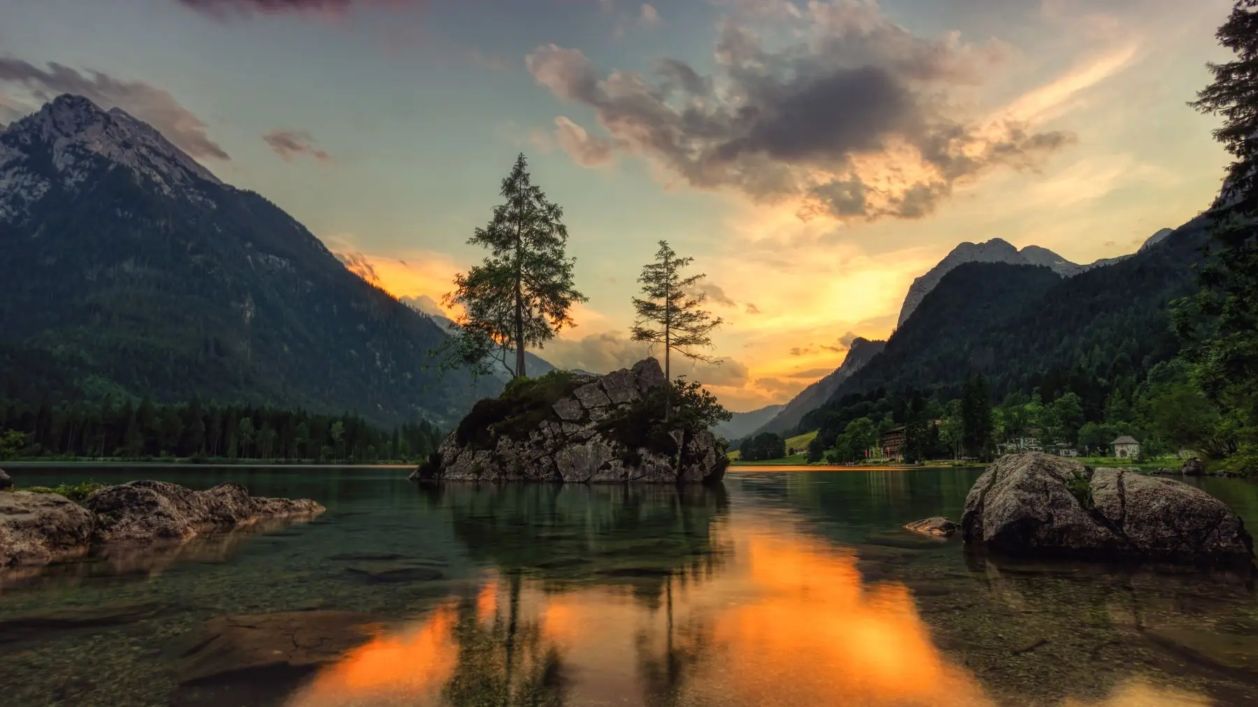 A mirror-still alpine lake reflecting the golden light of a mountain sunset